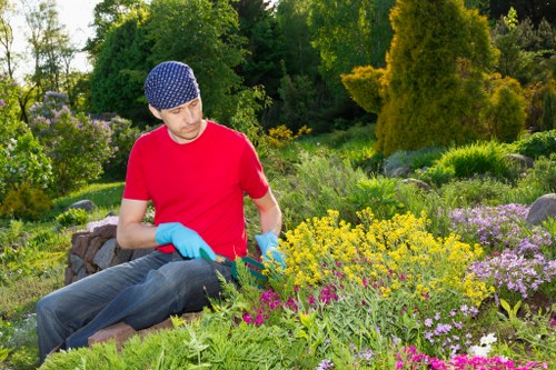 Worker setting up safety barriers near roadside garden